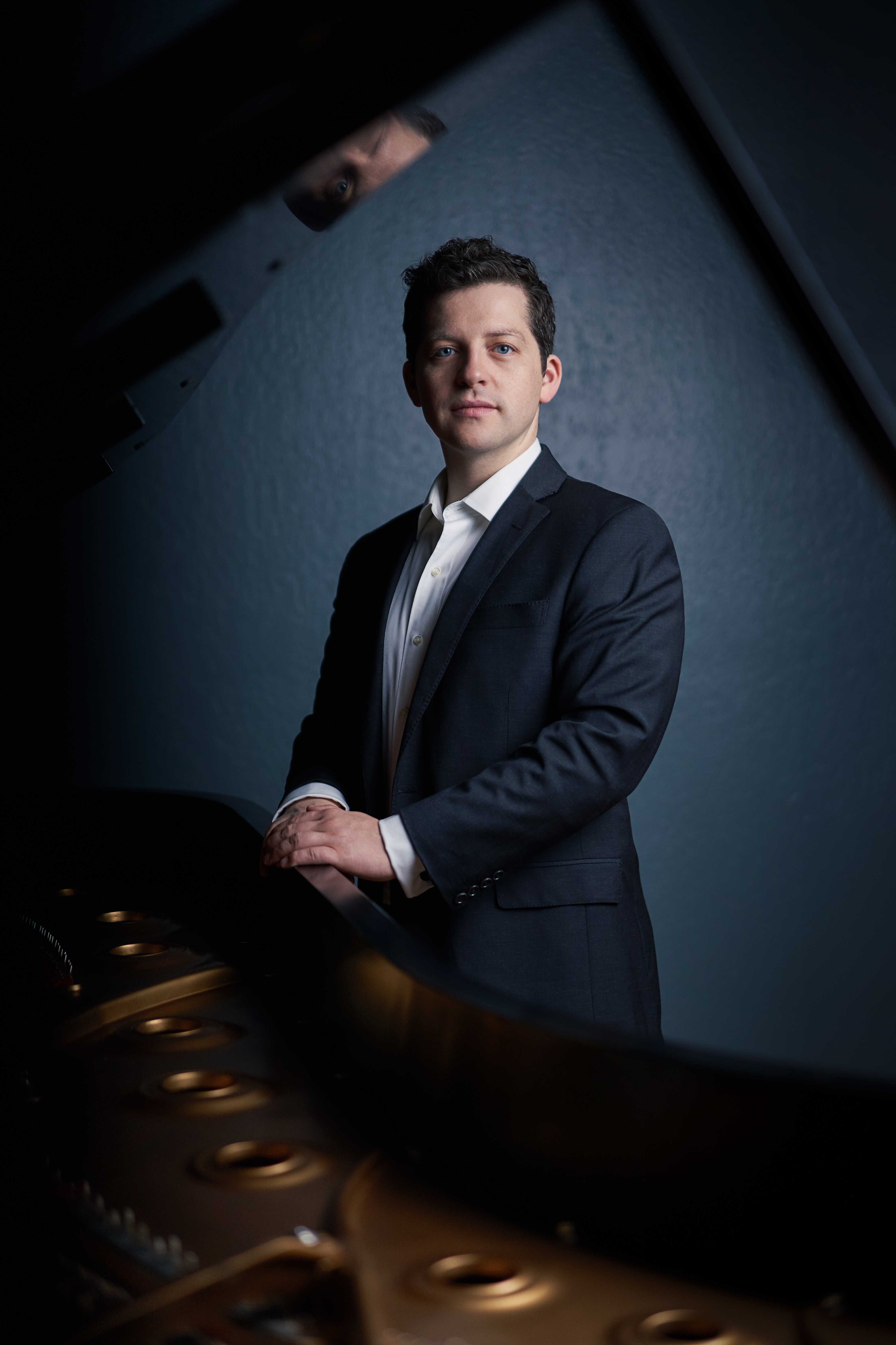 Portrait of Henry Kramer in front of a piano