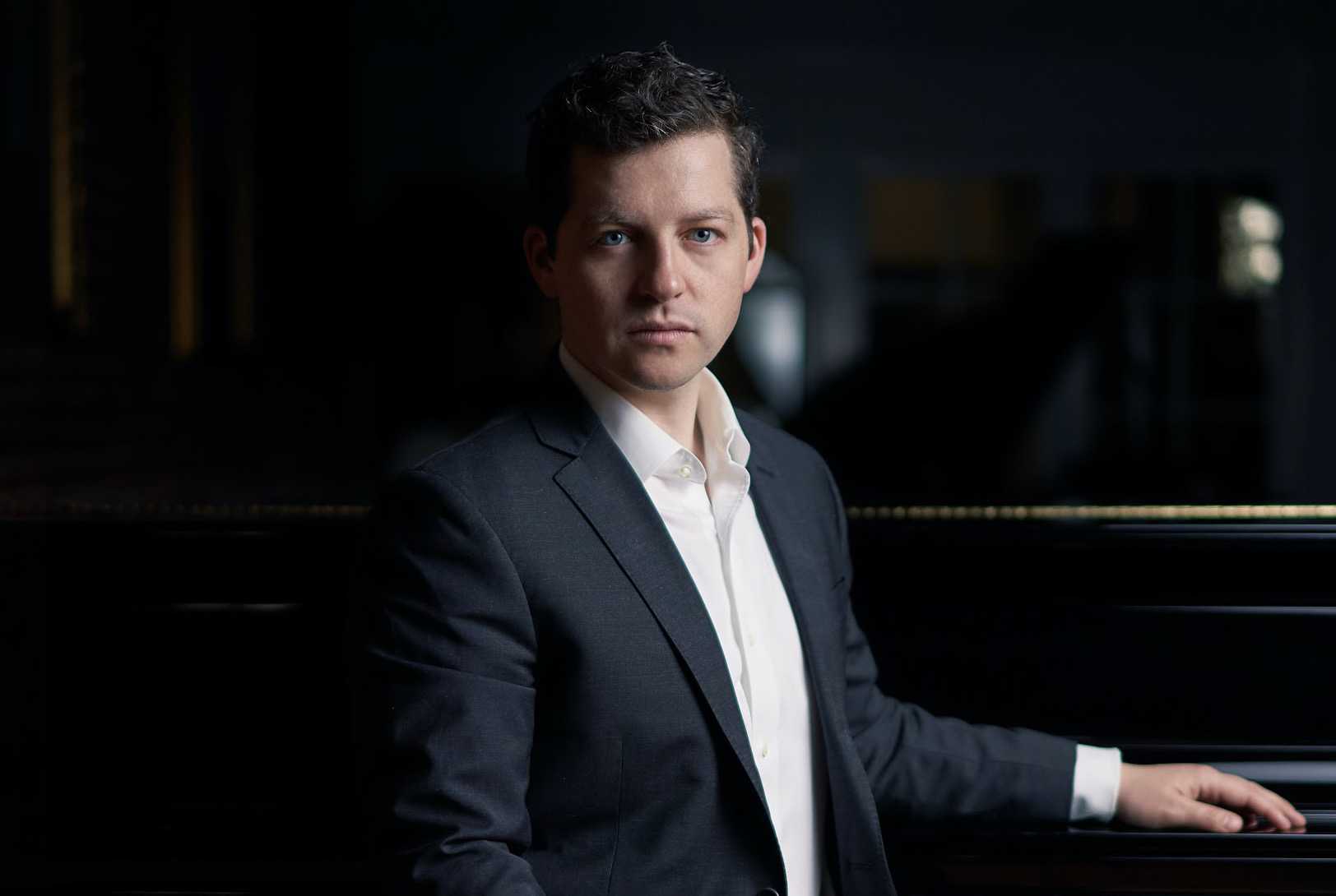 Portrait of Henry Kramer in front of a piano